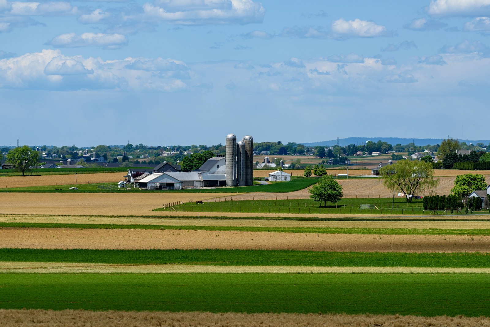 Aerial view of farmland with grain silos next to segmented crop fields